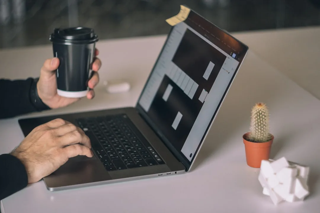 Designer reviewing prototypes on a laptop with coffee